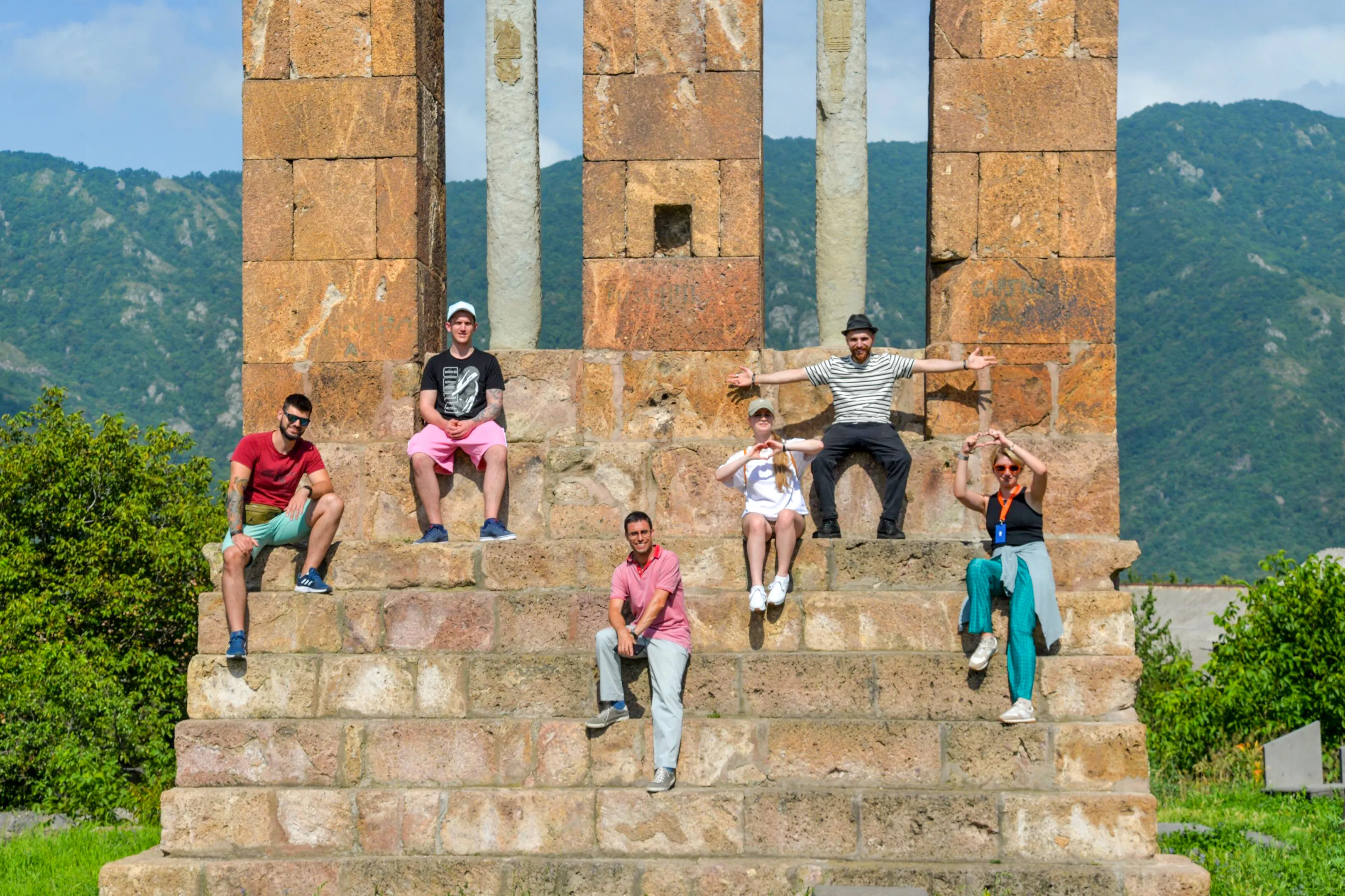 Group sitting on steps of Odzun Church during guided tour in Armenia.