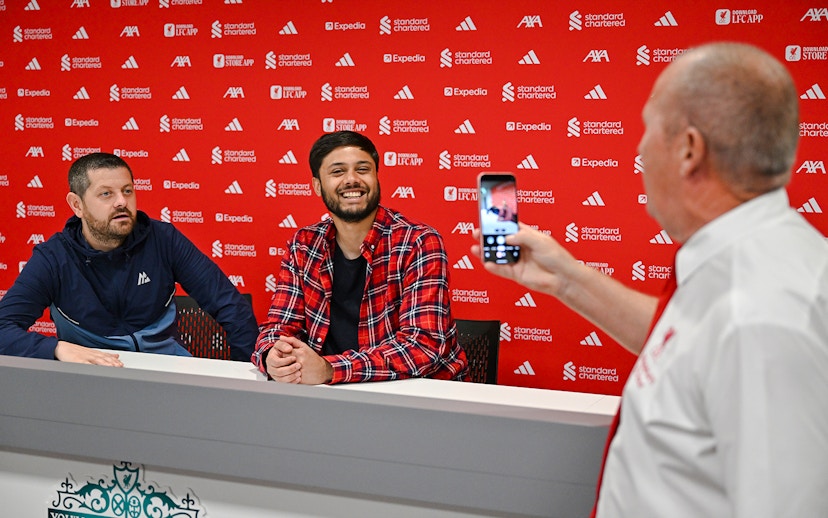 Guests in the press room at Anfield, with one taking a photo of two others at a table.