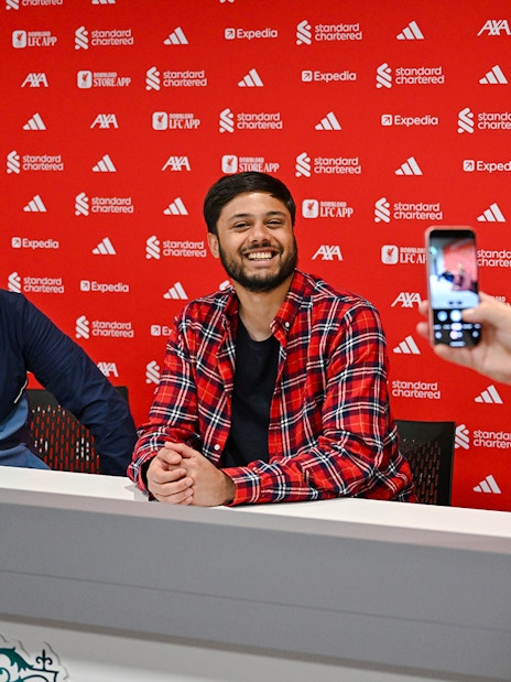 Guests in the press room at Anfield, with one taking a photo of two others at a table.