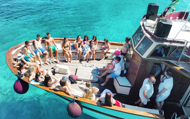 Tourists relaxing on a motorboat in La Maddalena Archipelago's clear waters.
