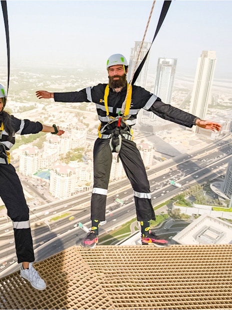 Participants on the Edge Walk at Sky Views Dubai with cityscape in background.