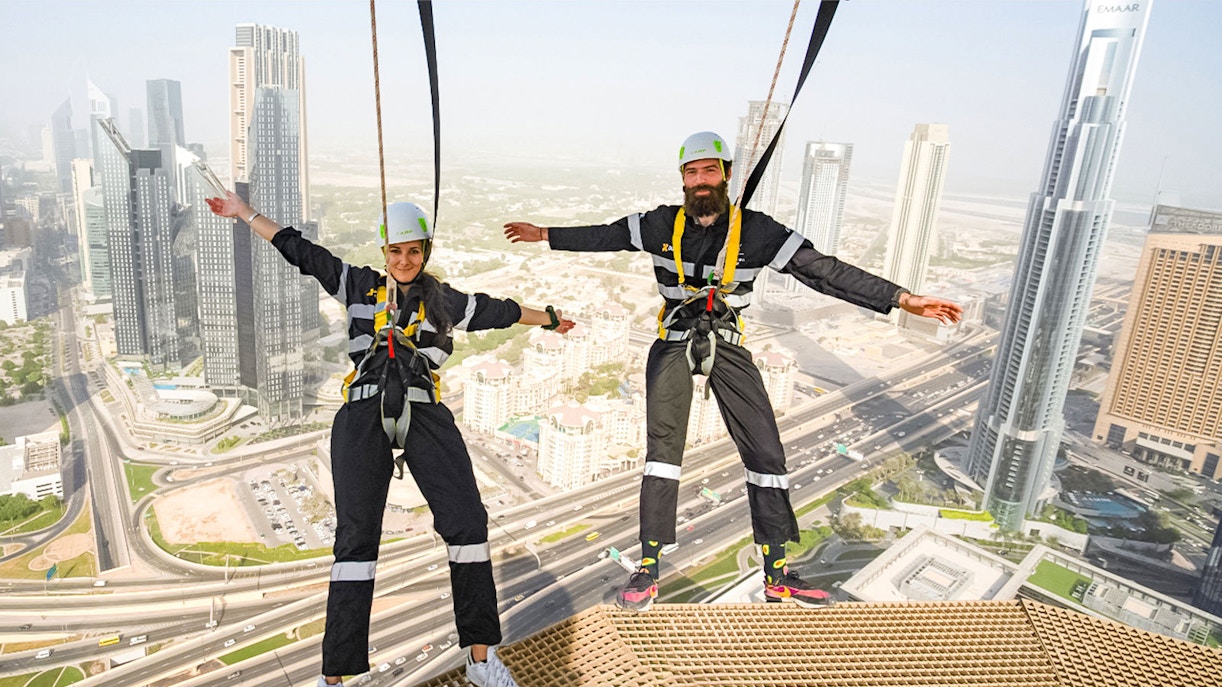 Participants on the Edge Walk at Sky Views Dubai with cityscape in background.