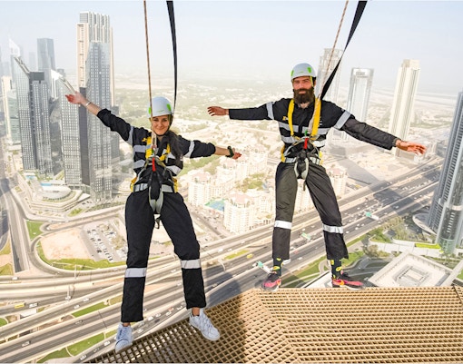 Participants on the Edge Walk at Sky Views Dubai with cityscape in background.