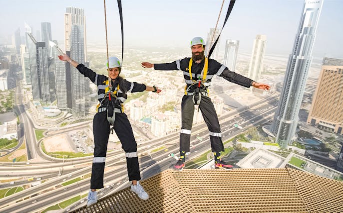 Participants on the Edge Walk at Sky Views Dubai with cityscape in background.