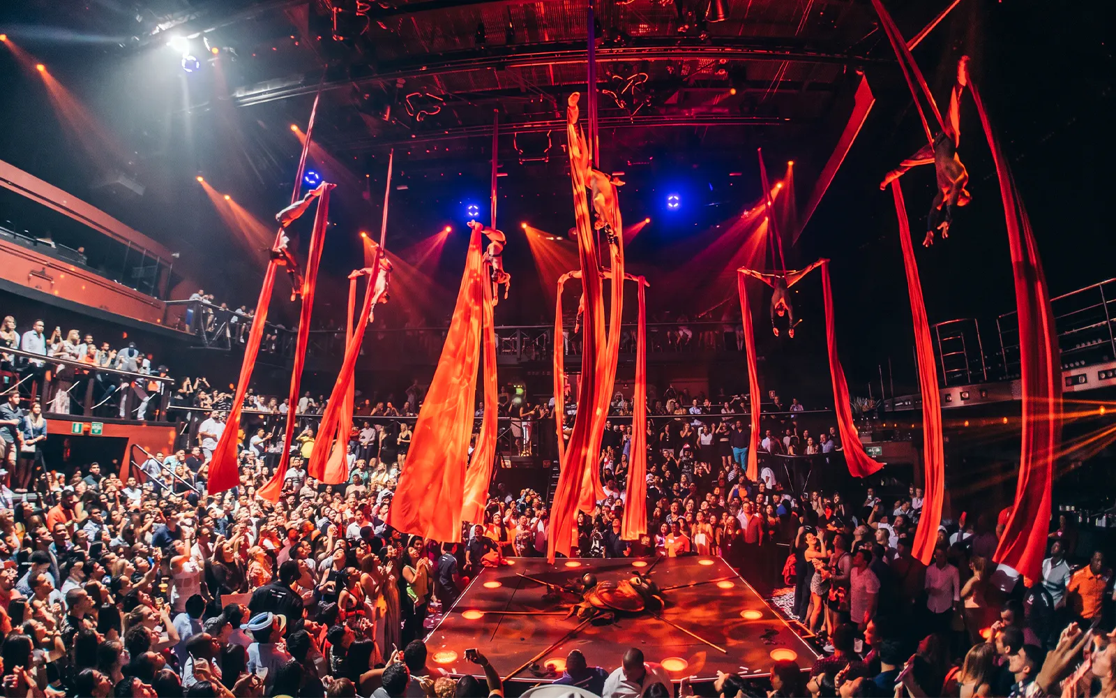 Aerial performers on red silks at Coco Bongo Club, Punta Cana with a lively crowd.