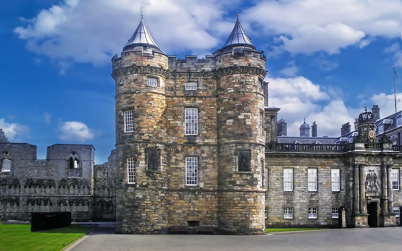 Holyroodhouse Palace facade with stone towers and blue sky in Edinburgh, Scotland.