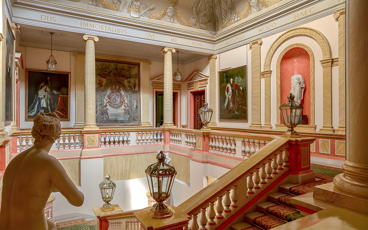 Staircase inside Liria Palace, Madrid, with classical statues and ornate paintings.