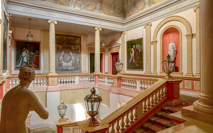 Staircase inside Liria Palace, Madrid, with classical statues and ornate paintings.