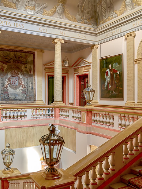Staircase inside Liria Palace, Madrid, with classical statues and ornate paintings.