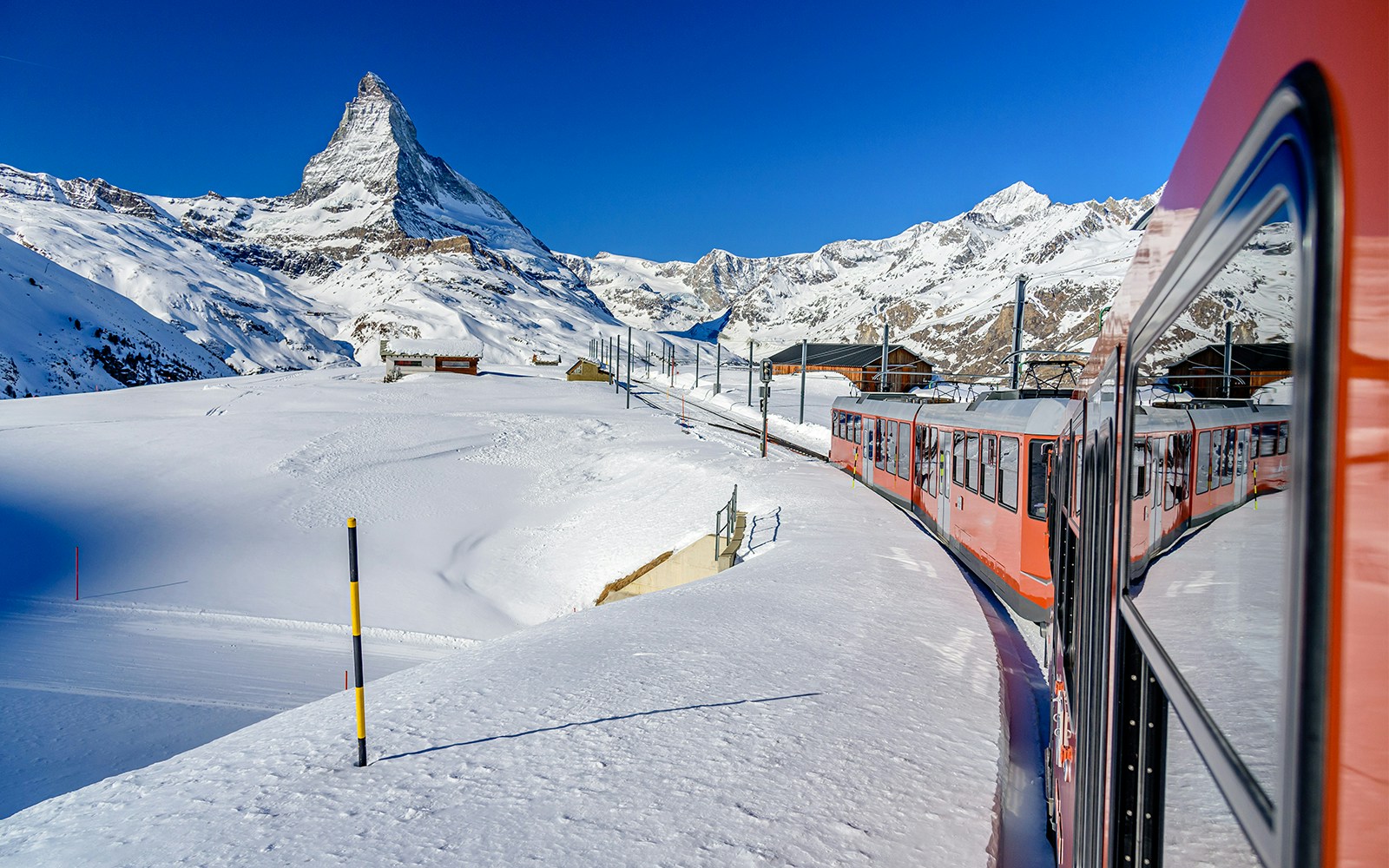 Gornergrat Railway train ascending Swiss Alps with Matterhorn in background.