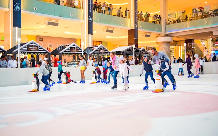 People ice skating at Dubai Ice Rink in a bustling mall environment.