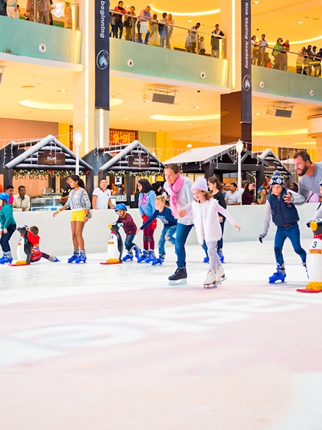 People ice skating at Dubai Ice Rink in a bustling mall environment.