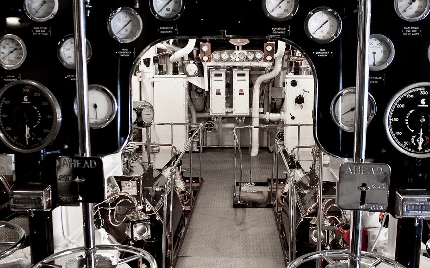 Engine room with control panels and gauges on a ship.