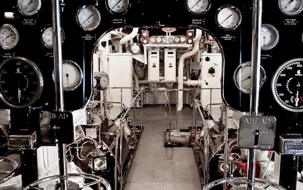Engine room with control panels and gauges on a ship.