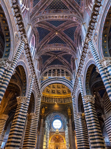 Siena Cathedral interior with striped columns and ornate vaulted ceiling.