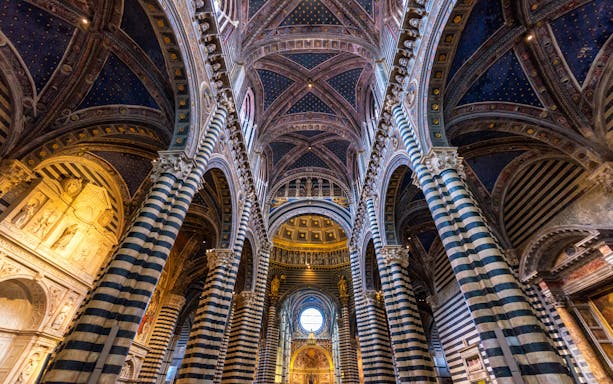 Siena Cathedral interior with striped columns and ornate vaulted ceiling.