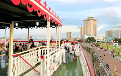 Riverboat cruise passengers enjoy views of New Orleans skyline and Mississippi River bridge.