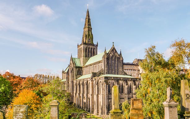Glasgow Cathedral surrounded by autumn trees on a sunny day.