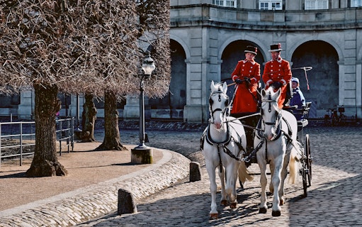 Horse-drawn carriage with guards in red uniforms at Amalienborg Palace, Copenhagen.