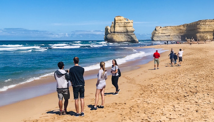 People walking on a beach near the 12 Apostles during the Great Ocean Road Reverse Tour, Melbourne.