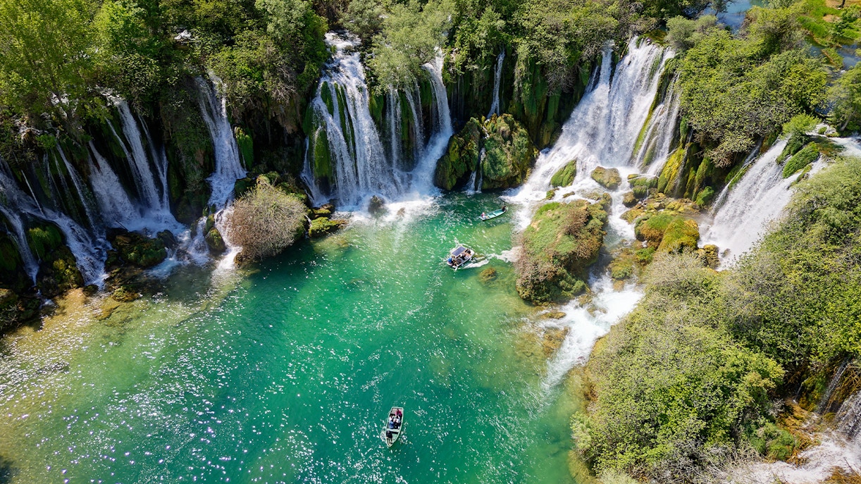 Aerial view of Kravica Waterfall in Bosnia and Herzegovina with lush greenery surrounding the cascading water.