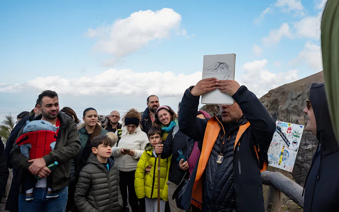 Tour group listening to a guide at Vesuvius National Park near Naples, Italy.