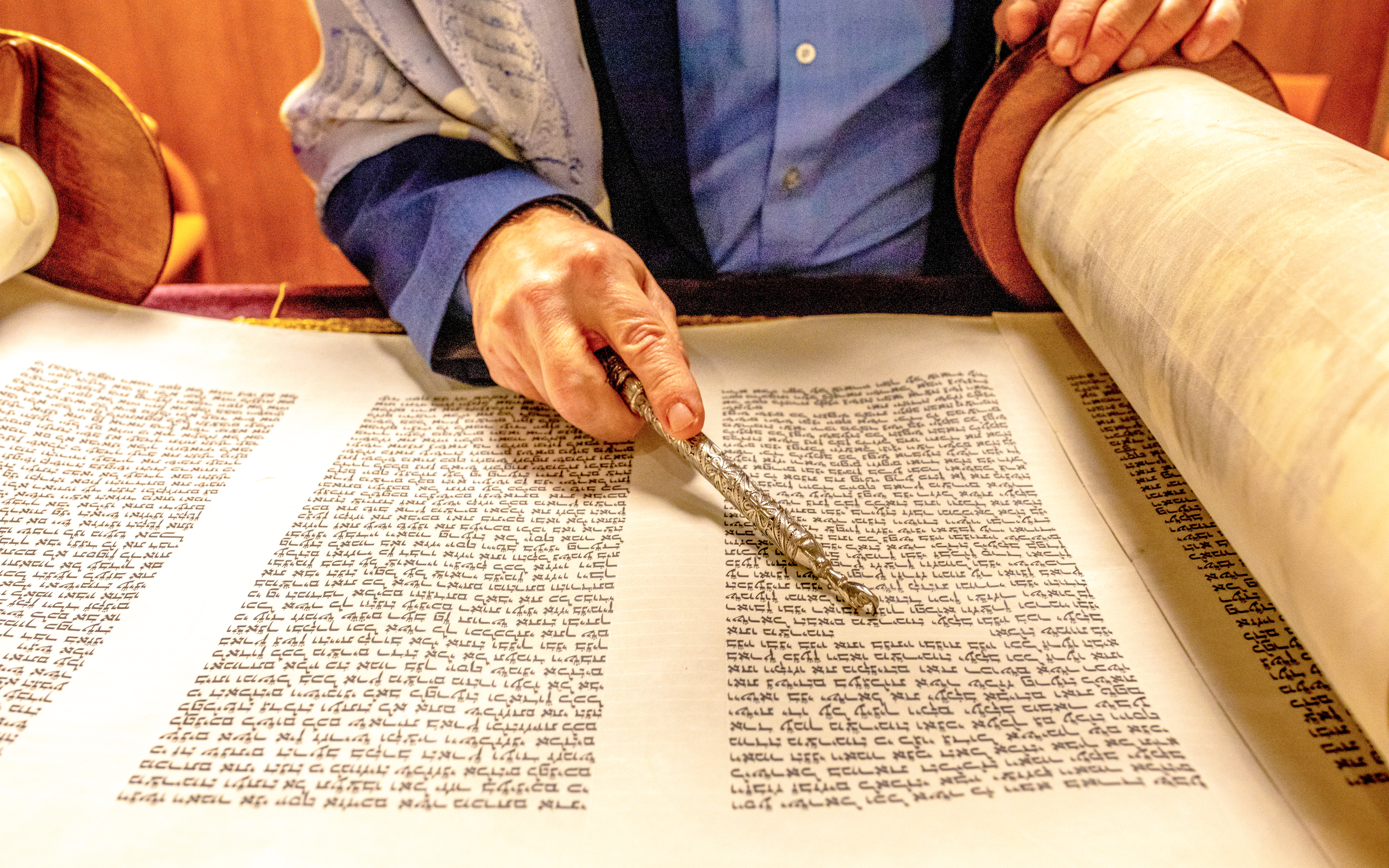 Rabbi reading from a Sefer Torah with a yad pointer.