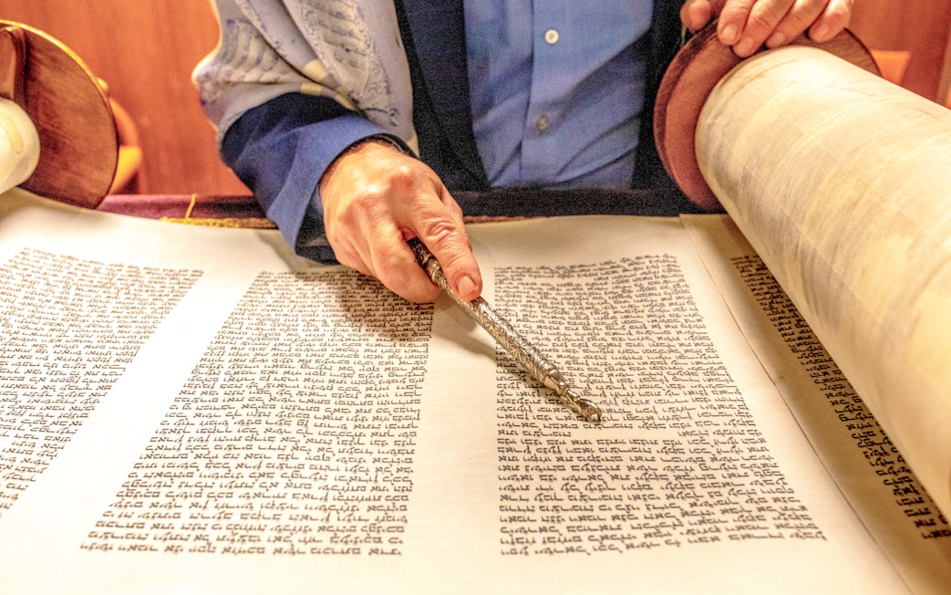 Rabbi reading from a Sefer Torah with a yad pointer.