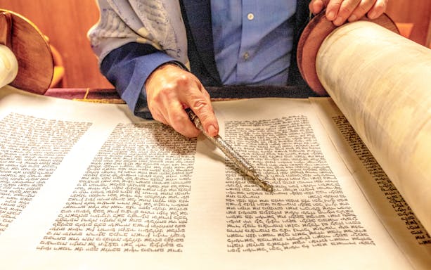 Rabbi reading from a Sefer Torah with a yad pointer.