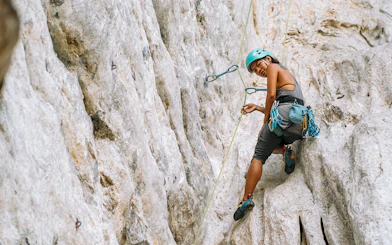 Female climber scaling limestone cliff in Krabi, Thailand.