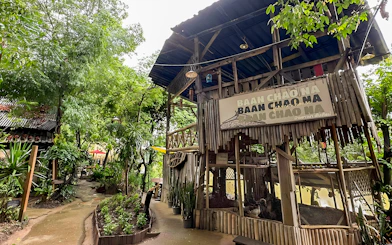 Mae Ping River Cruise stop at Baan Chao Na, featuring lush greenery and rustic wooden structures.