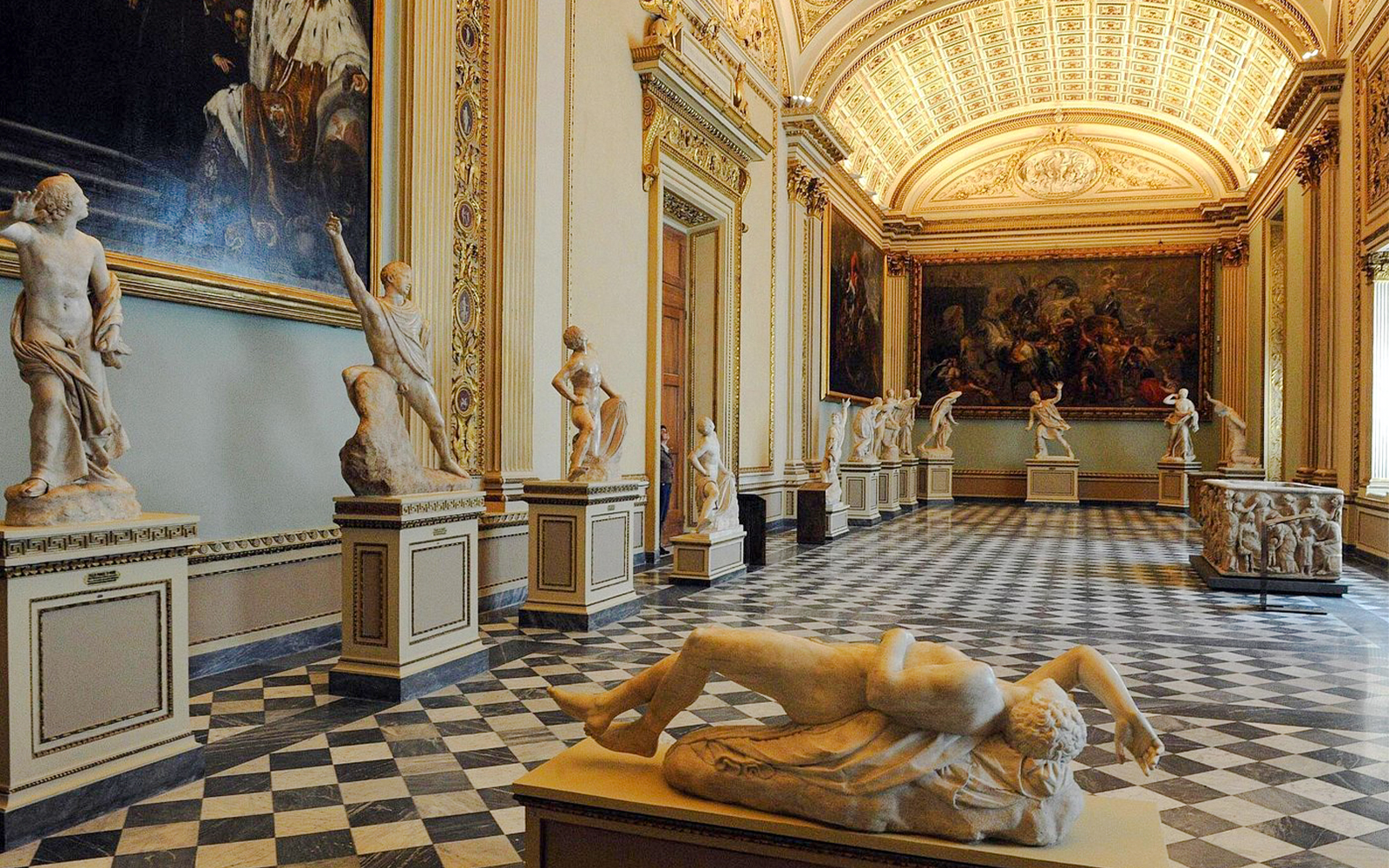 Uffizi Gallery hall with classical sculptures and ornate ceiling.