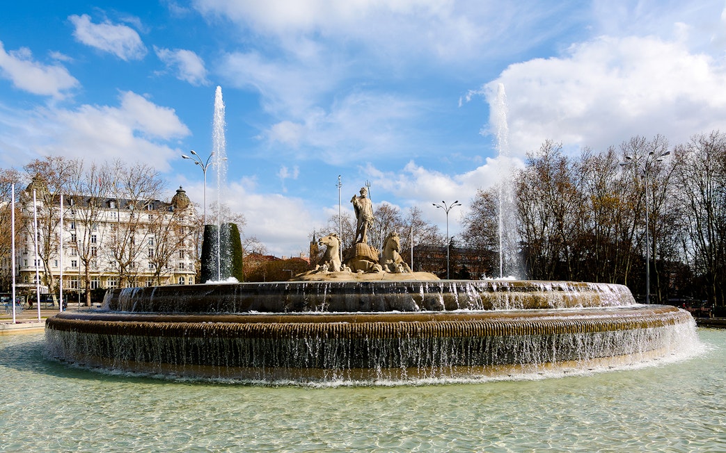 Fountain of Neptune with water jets in Madrid's Plaza de Cánovas del Castillo.