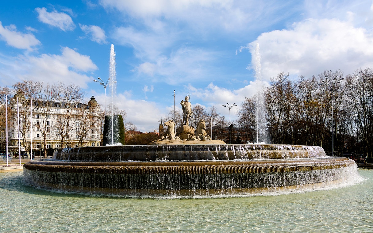 Fountain of Neptune with water jets in Madrid's Plaza de Cánovas del Castillo.
