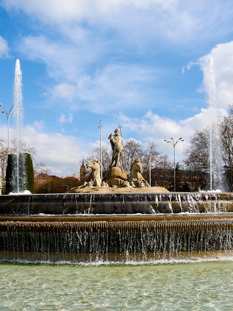 Fountain of Neptune with water jets in Madrid's Plaza de Cánovas del Castillo.