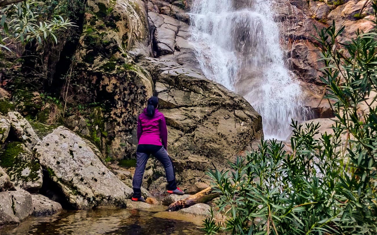 Person standing by a waterfall in Villacidro, Cagliari during a guided history and culture trek.
