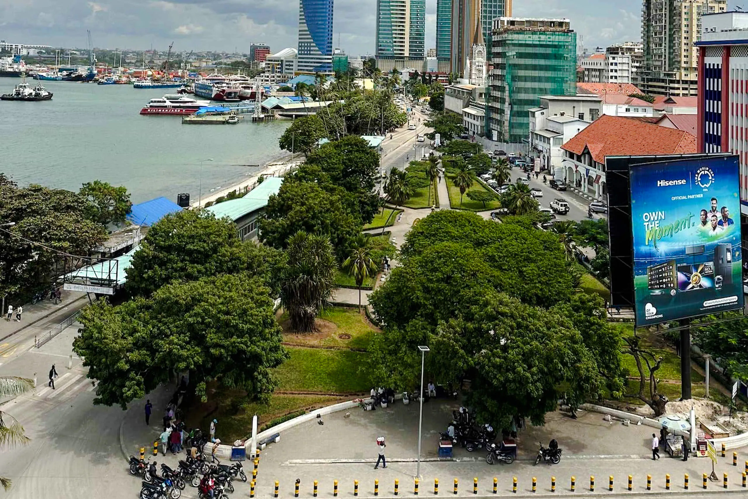 Dar es Salaam cityscape with waterfront, high-rise buildings, and green park area.