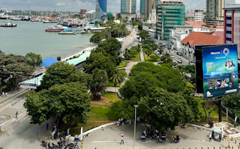 Dar es Salaam cityscape with waterfront, high-rise buildings, and green park area.
