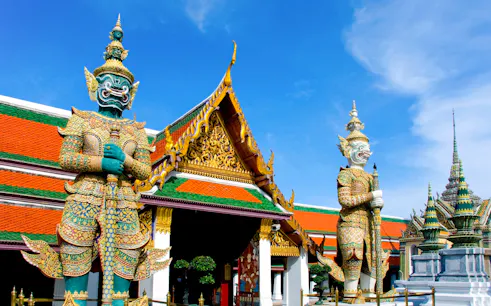 Giant guardian statues at The Grand Palace, Bangkok, on a sunny day.
