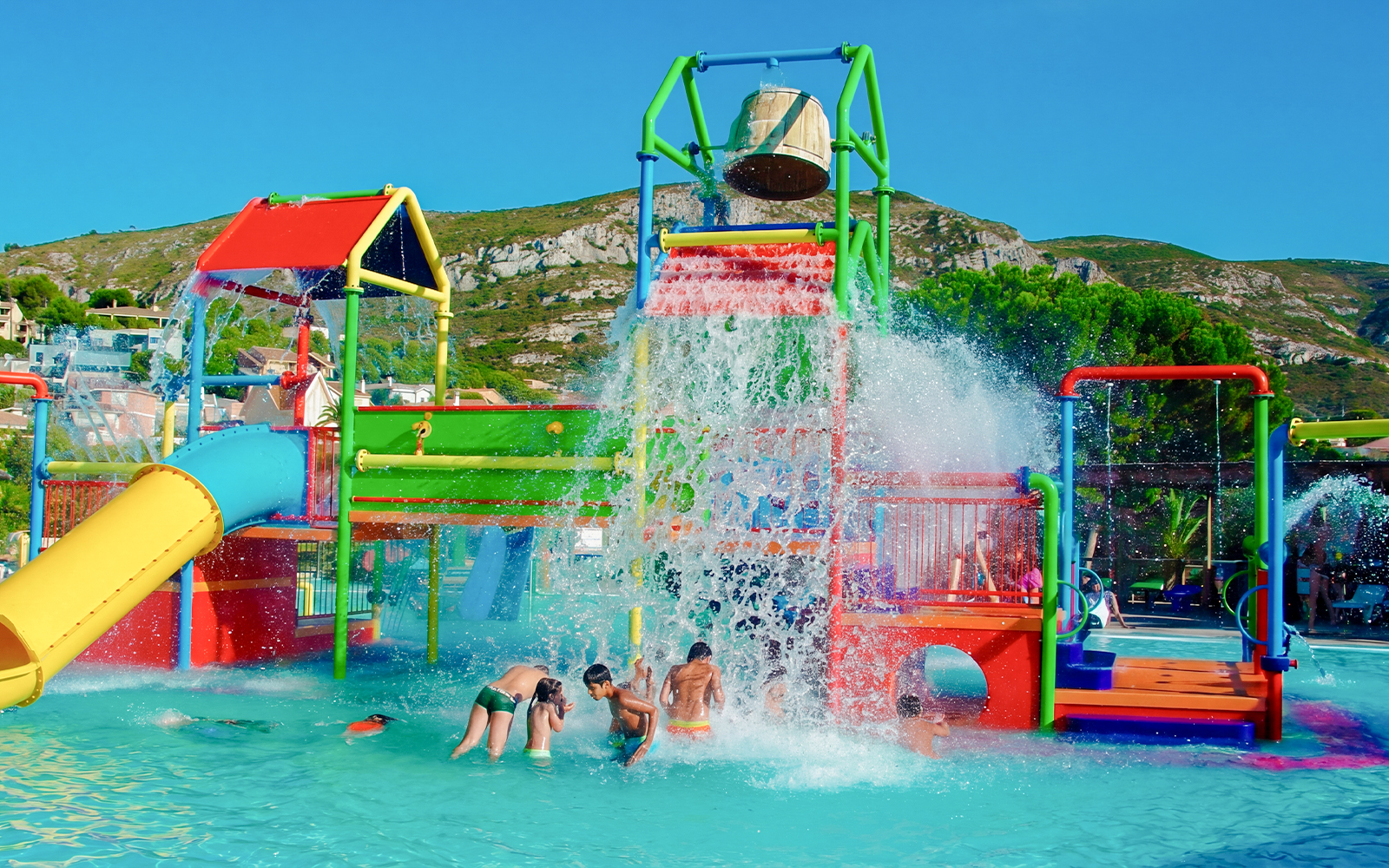 Children playing under water bucket at Aquopolis Cullera mini park.