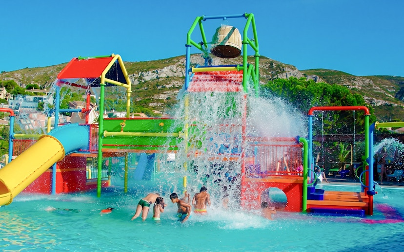 Children playing under water bucket at Aquopolis Cullera mini park.