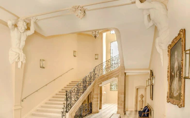 Staircase with ornate railing and sculptures at Caumont Centre d’Art, Aix-en-Provence.
