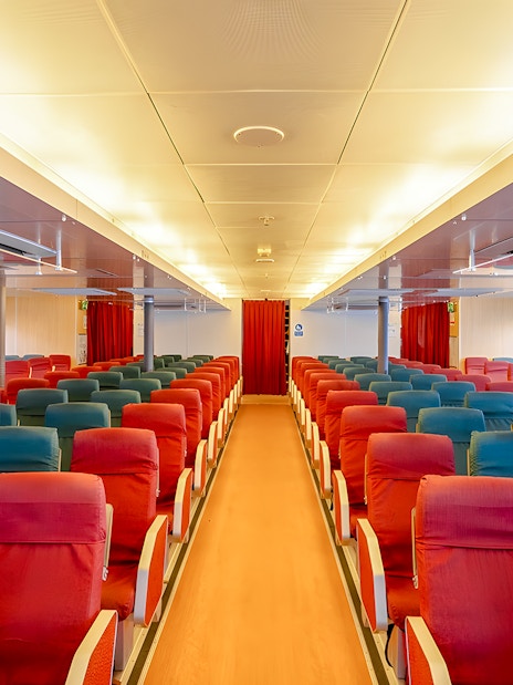 Ferry interior with rows of red and blue seats on the Singapore to Bintan Resorts route.