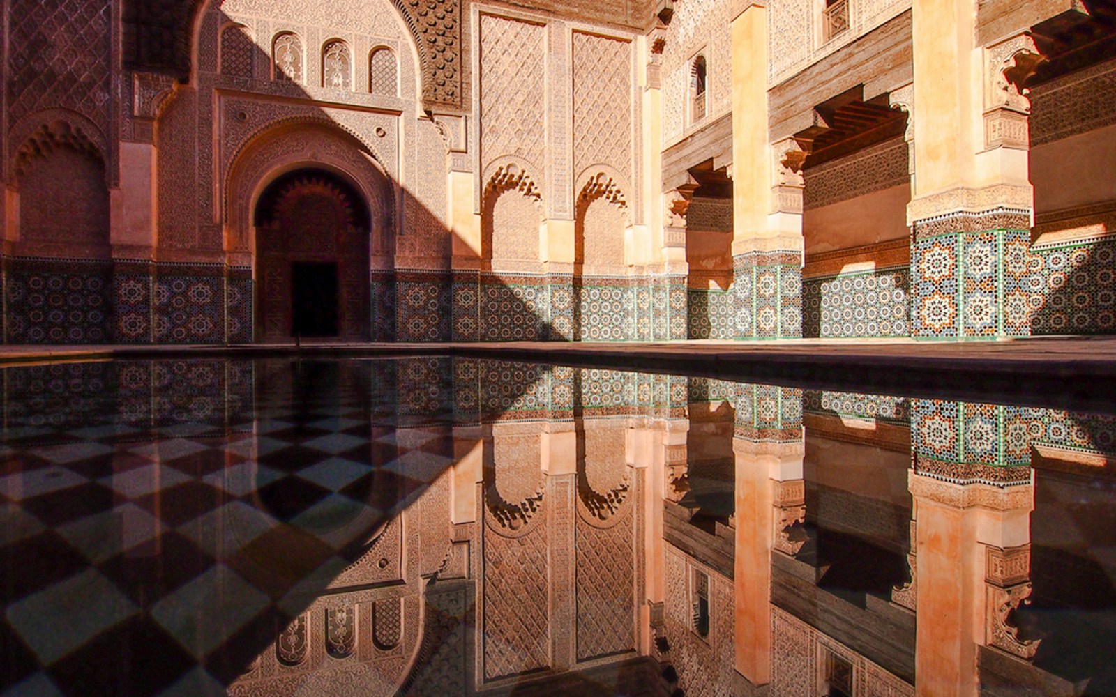 Ben Youssef Madrasa courtyard with intricate tilework in Marrakech, Morocco.