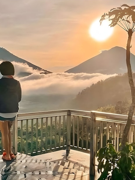 Woman viewing Mount Batur sunrise from a cafe in Kintamani, Bali.