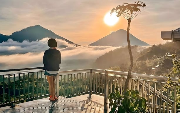 Woman viewing Mount Batur sunrise from a cafe in Kintamani, Bali.