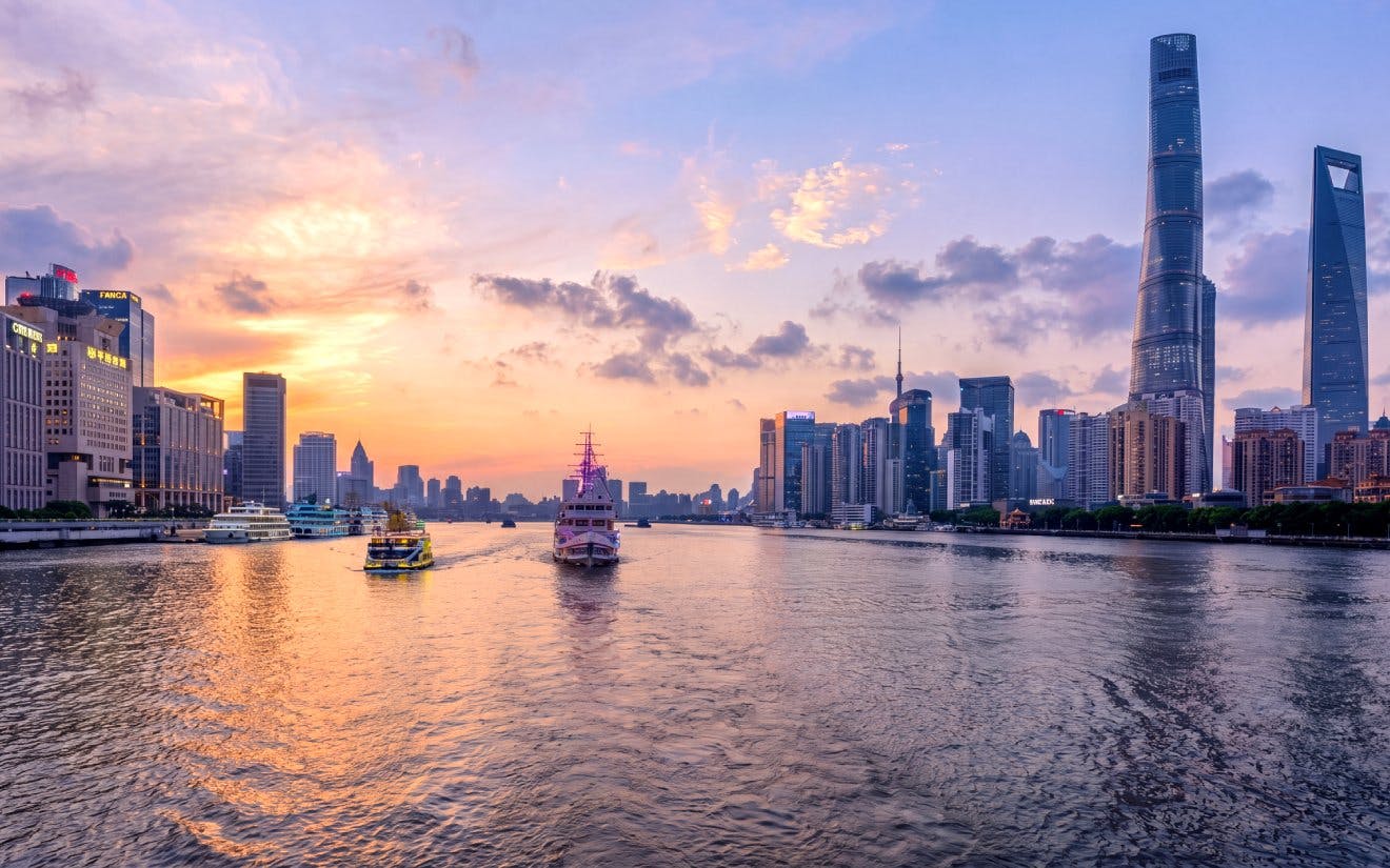 Shanghai skyline at sunset with historic Bund and modern Lujiazui across Huangpu River.