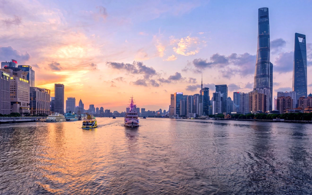 Shanghai skyline at sunset with historic Bund and modern Lujiazui across Huangpu River.