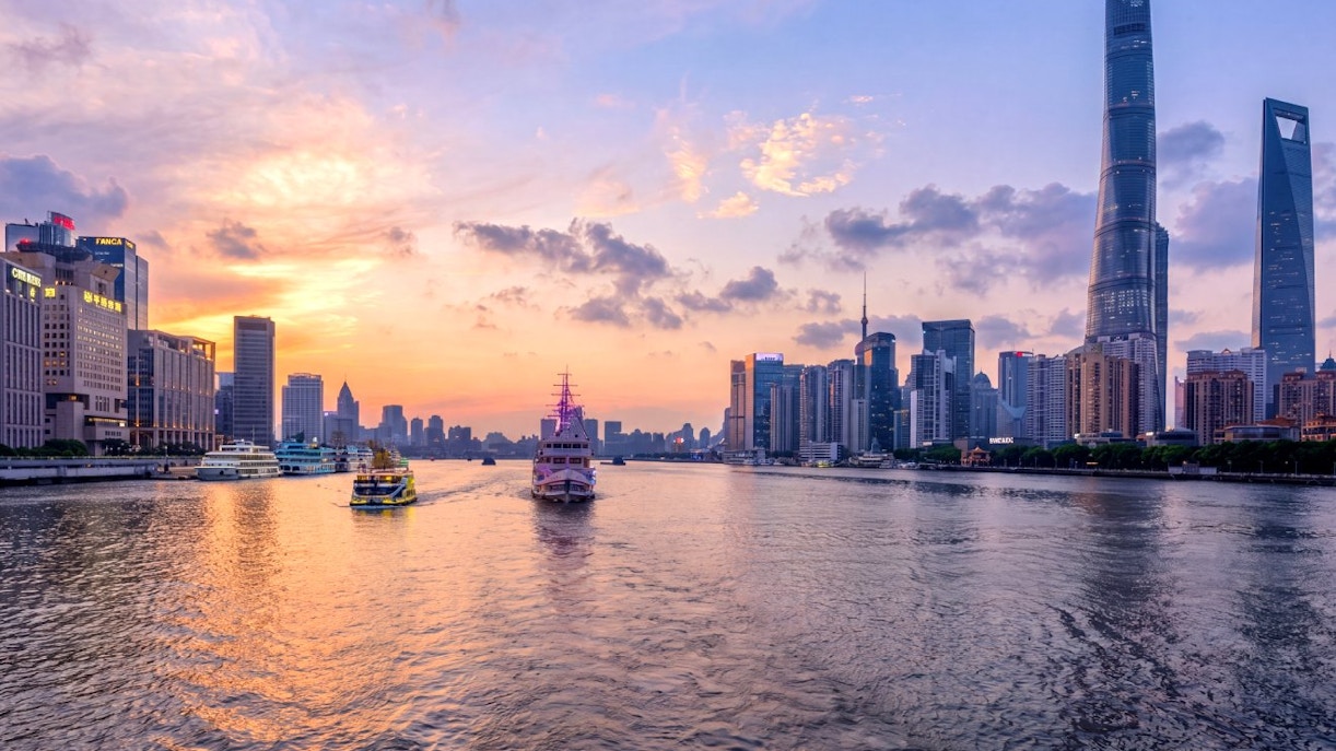 Shanghai skyline at sunset with historic Bund and modern Lujiazui across Huangpu River.