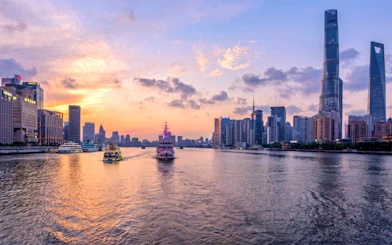 Shanghai skyline at sunset with historic Bund and modern Lujiazui across Huangpu River.